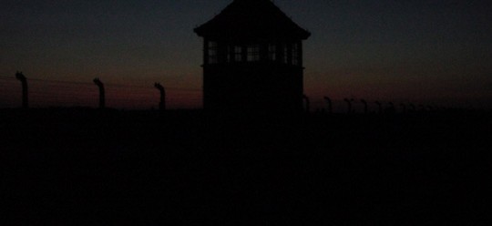Foto der Frontseite des Konzentrationslagers Auschwitz - Brikenau mit Wachturm der SS bei Nachteinbruch 2005