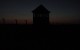 Foto der Frontseite des Konzentrationslagers Auschwitz - Brikenau mit Wachturm der SS bei Nachteinbruch 2005